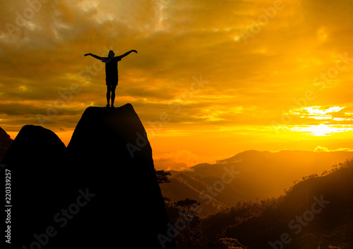 She  Silhouette  photo. She is show hand and standing on cliff. She is happy and good feel  for nature. lifestyle   freedom   She is see sun set. Photo concept  achievement and Silhouette.