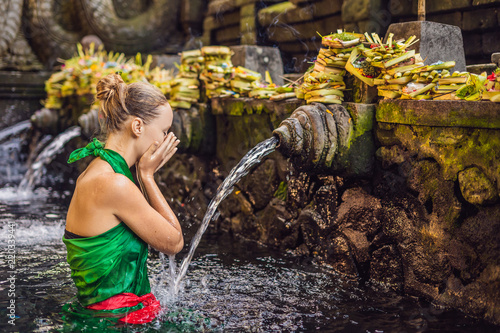 Woman in holy spring water temple in bali. The temple compound consists of a petirtaan or bathing structure, famous for its holy spring water photo