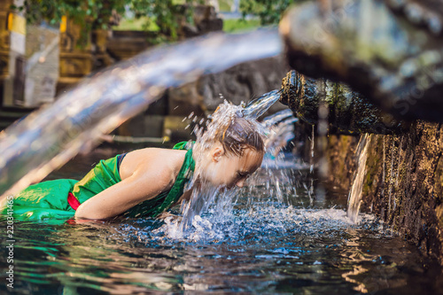 Woman in holy spring water temple in bali. The temple compound consists of a petirtaan or bathing structure, famous for its holy spring water photo