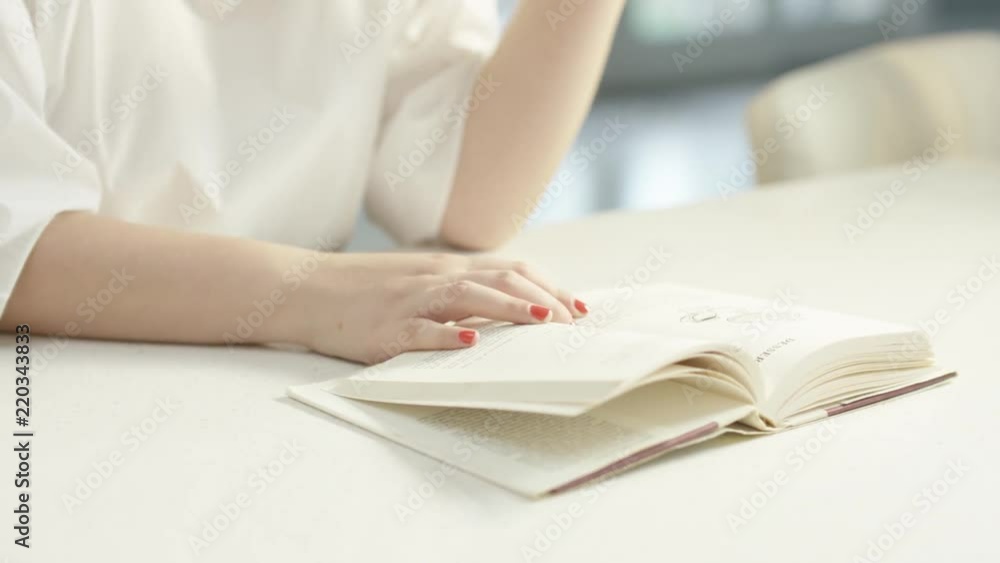 Woman Flipping through Book on Counter Woman Flipping through Book on Counter