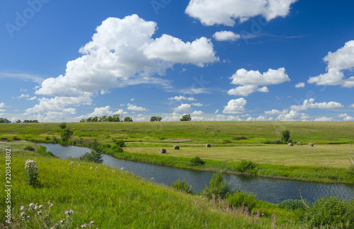 Sunny summer landscape with river,fields,green hills and beautiful clouds in blue sky.River Upa in Tula region,Russia. 