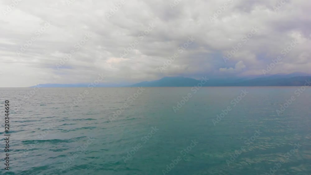 Low forward moving drone shot on the water showing waves, and beautiful mountains in the background Low forward moving drone shot on the water showing waves, and beautiful mountains in the background