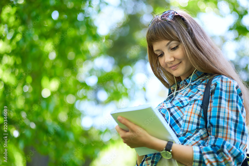teenage girl student writing in notebook in park. Preparation for exams at college or university teenage girl student writing in notebook in park. Preparation for exams at college or university