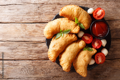 fried panzerotti with a filling of tomatoes, herbs and mozzarella close-up. horizontal top view