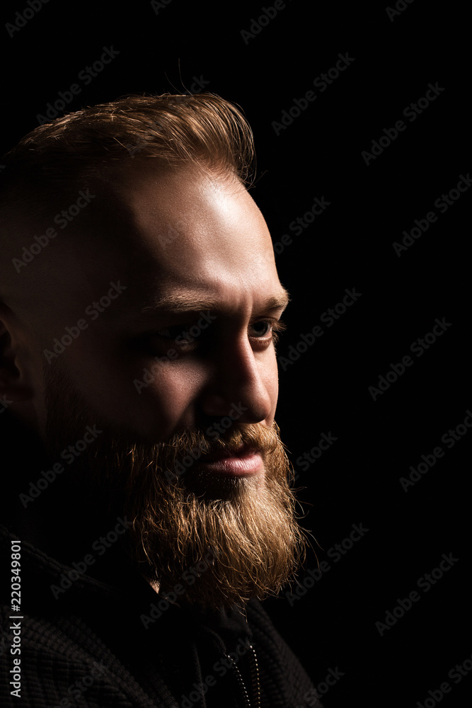male portrait of a guy with a beard on a black background close-up