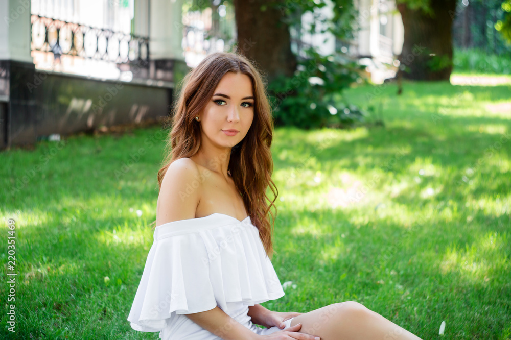 A young woman in a white dress sitting in the park on the road. A young woman in a white dress sitting in the park on the road.