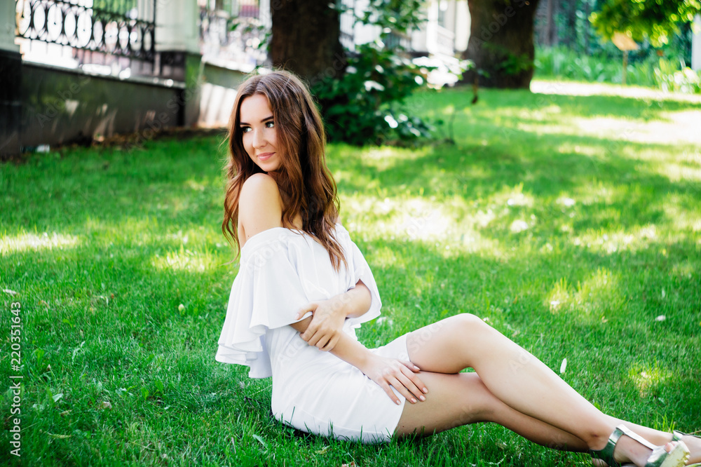 A young woman in a white dress sitting in the park on the road. A young woman in a white dress sitting in the park on the road.