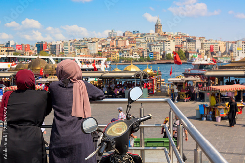 Muslim women looking Istanbul panorama with Galata tower during summer sunny day. Istanbul, Turkey.