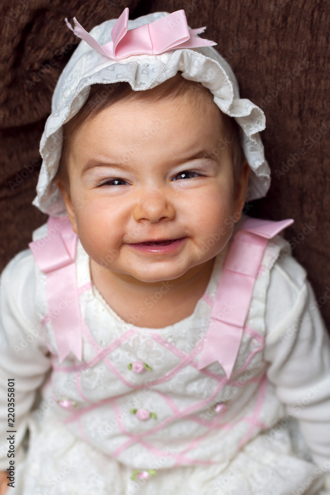 Adorable Baby Girl Smiling With a Scrunched Face She is Wearing a White Floral Outfit Adorable Baby Girl Smiling With a Scrunched Face She is Wearing a White Floral Outfit
