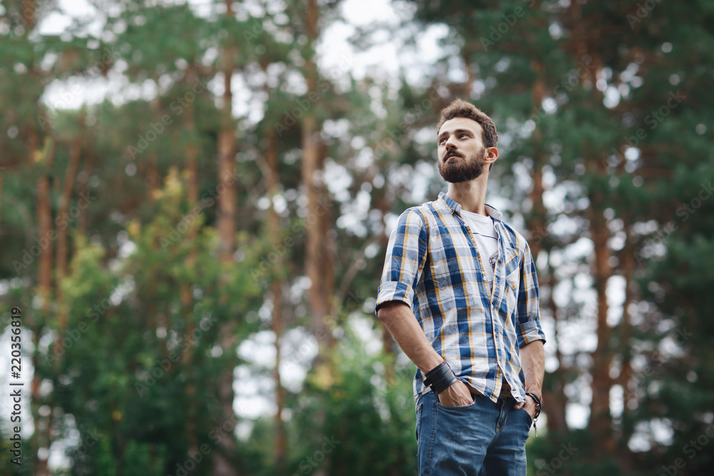 Attractive young bearded hipster posing in the park.