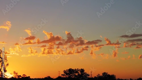 Sunset timelapse of with boiling light cumulus clouds in lurid orange with a natural landscape skyline