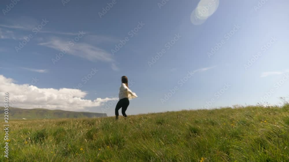 Woman dancing in filed of flowers in Iceland on adventure vacation Woman dancing in filed of flowers in Iceland on adventure vacation