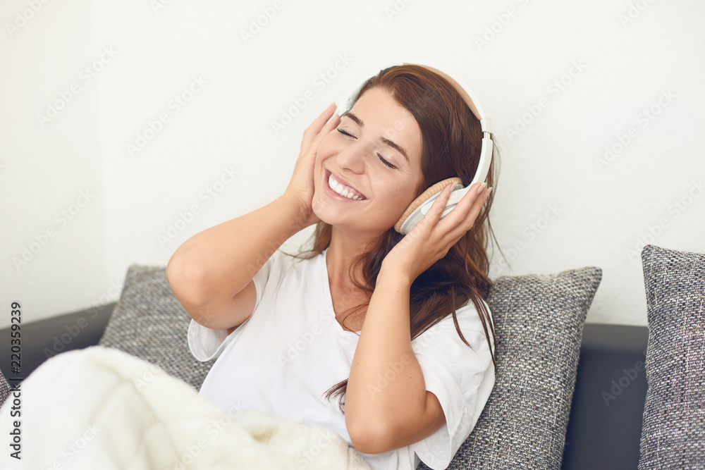 Hübsche junge Frau liegt auf dem Sofa und hört Musik Hübsche junge Frau liegt auf dem Sofa und hört Musik