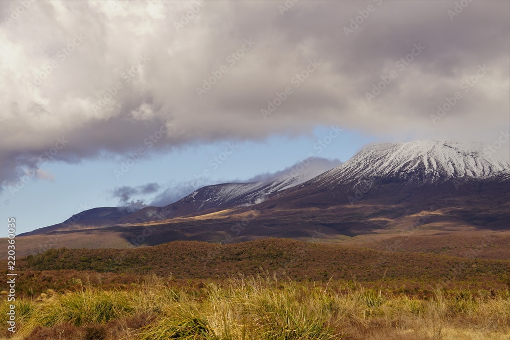 Obraz premium clouds and shadows over snow capped mountains and foothills in spring