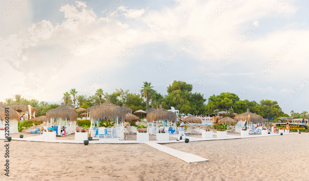 VIP zone on the beach in the form of a personal bungalow with a roof made of palm branches and snow-white sofas