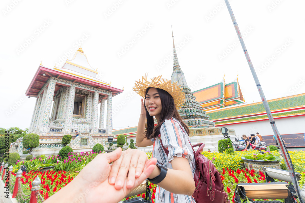 Tourist asian women leading boyfriend hand to travel in buddha temple of dawn