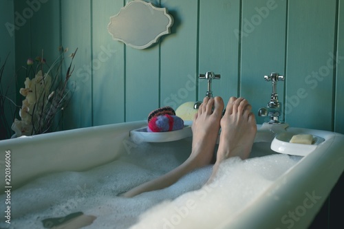 Woman taking bath in bathtub at bathroom photo