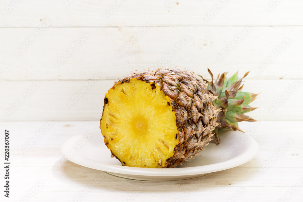 half organic pineapple on a plate, white painted wooden background with copy space half organic pineapple on a plate, white painted wooden background with copy space