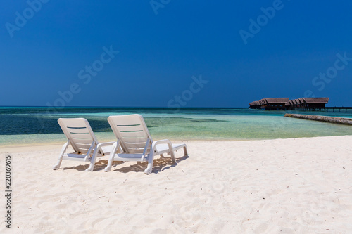 Sun lounges on an empty white Maldivian beach