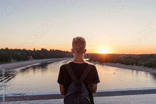 Tableau sur toile on the pier with steel railing above the water is a guy a young man with his bac