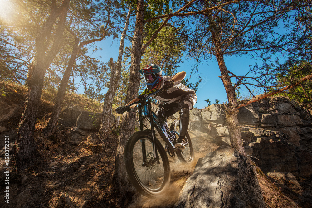 Φωτογραφία Mountain biker on forest trail. Male cyclist rides the rock