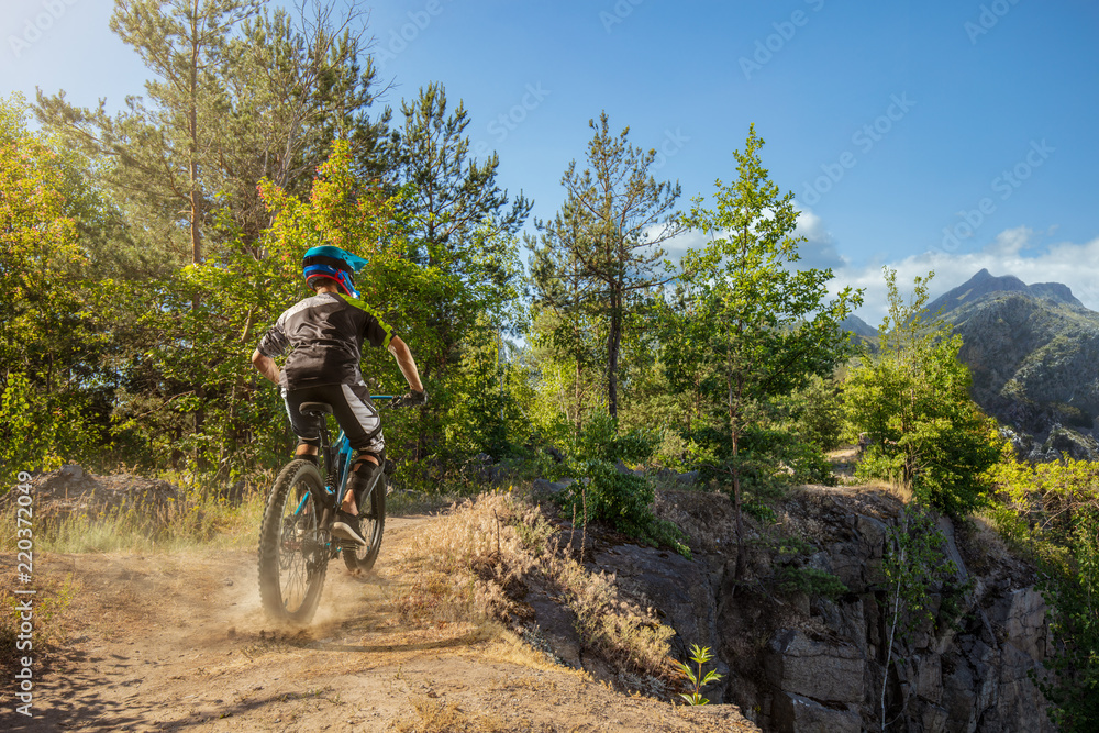 Mountain biker on forest trail. Male cyclist rides the rock
