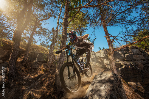 Mountain biker on forest trail. Male cyclist rides the rock photo