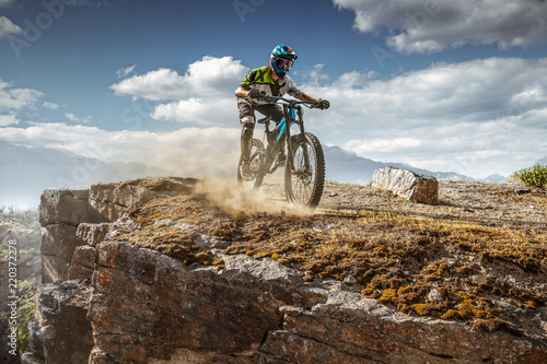 Mountain biker on stone trail. Male cyclist rides the rock