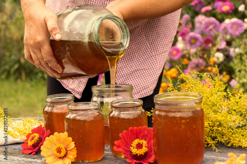 Woman holding bottle of honey. Autumn harvest.