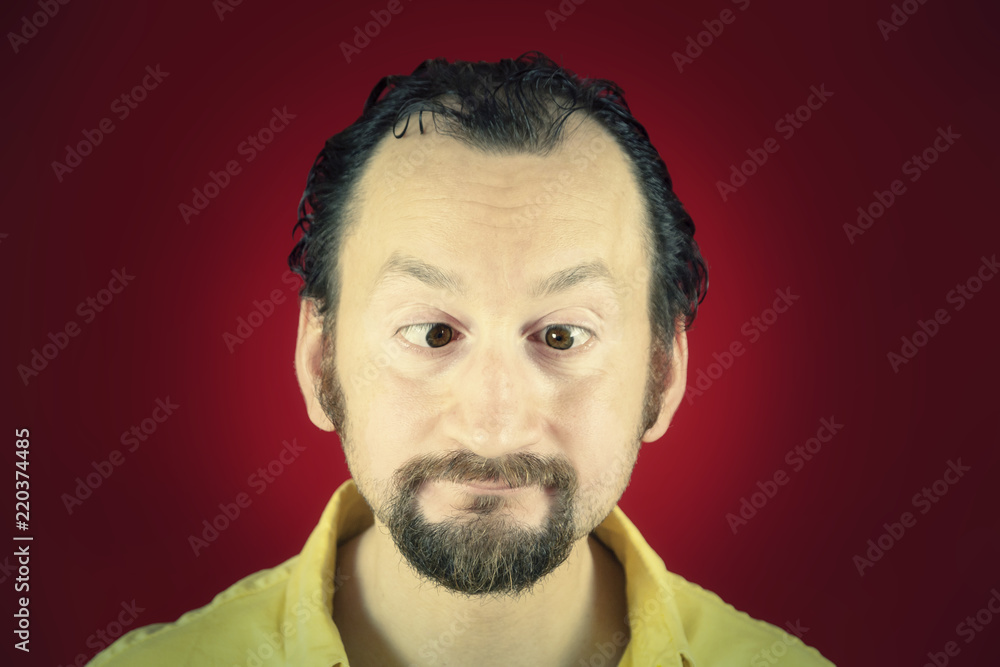 A funny ugly man with his eyes crossed. Vignette, red background