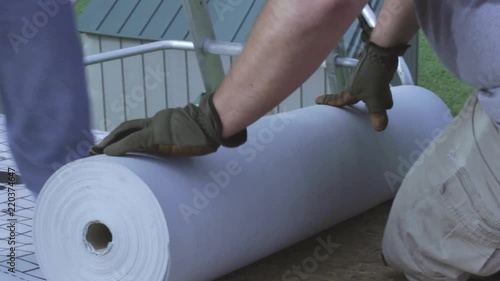 Workers roll out fabric to seal a roof. photo