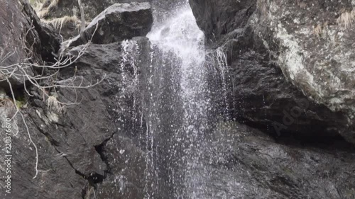 Water falling down from a medium waterfall with dark brown rocks_slomo photo