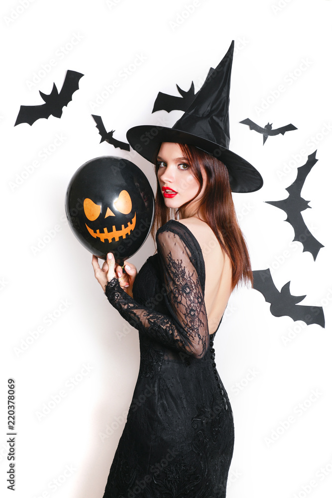 Obraz premium sexy beautiful woman in black witch halloween costumes with balloon on party over white background