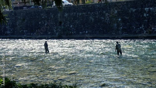 This Fisherman is fly fishing in a river trying to catch Trout on a sunny summer morning in Breil Sur Roja, Italy. photo