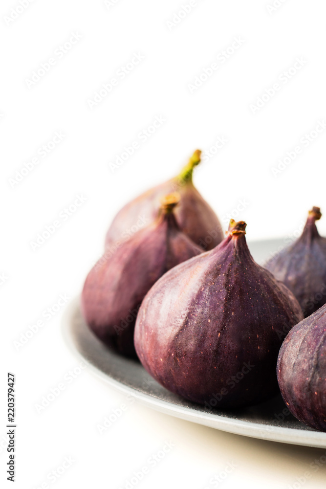 Fresh figs on grey plate isolated on white Fresh figs on grey plate isolated on white