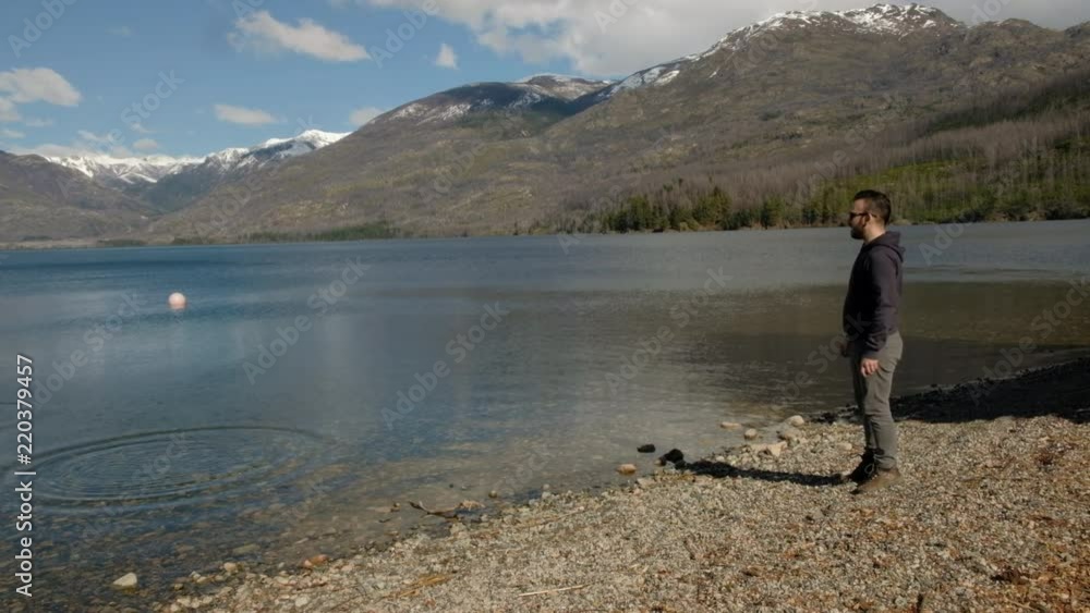 Young caucasian man with sunglasses throwing rocks to the lake Young caucasian man with sunglasses throwing rocks to the lake