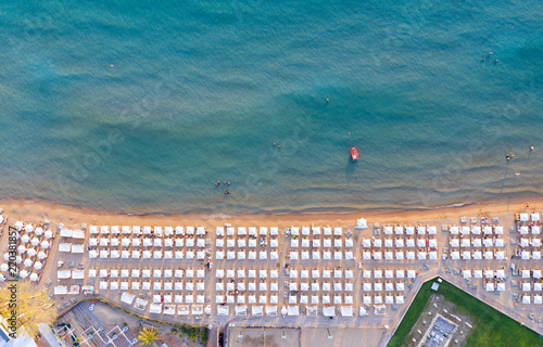 Luftaufnahme des beliebten Astir Strand in Vouliagmeni, Athen, Griechenland, mit symmetrisch angeordneten Sonnenschirmen und Sonnenliegen