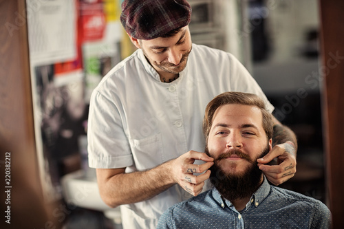 smiling male barber is serving his client