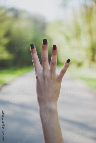 Girl demonstrating a number four (4) gesture against sunny green background. © Yurii Zymovin