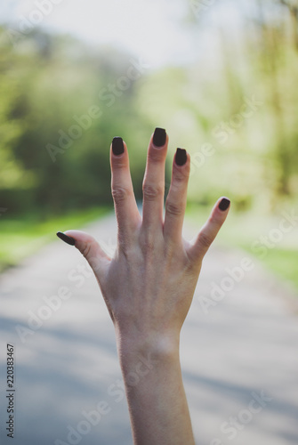 Girl demonstrating a number five (5) gesture against sunny green background. © Yurii Zymovin