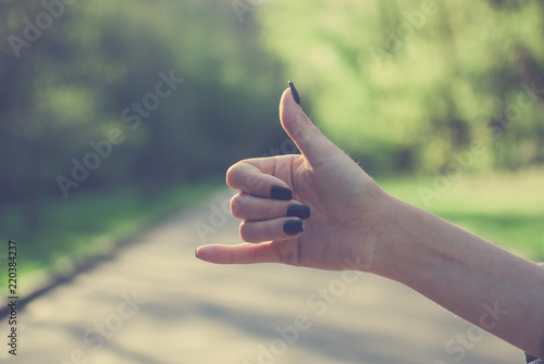 Girl demonstrating a shaka sign against spring forest covered with sunlight. Vintage retro colors © Yurii Zymovin