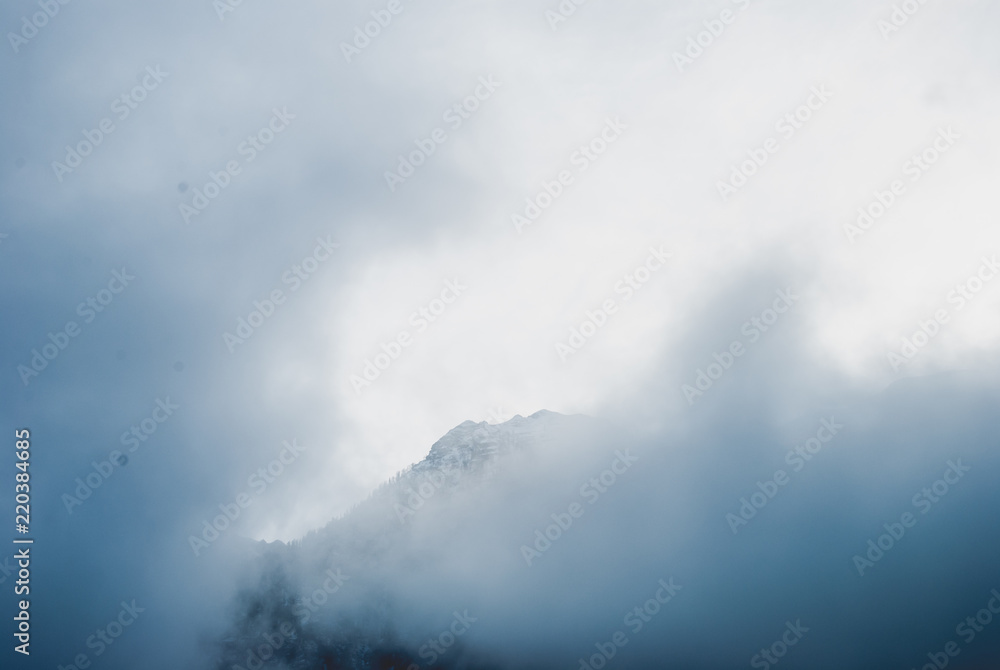 White summit of mountain covered with snow. Dense spring fog in Austrian Alps. Vintage colors