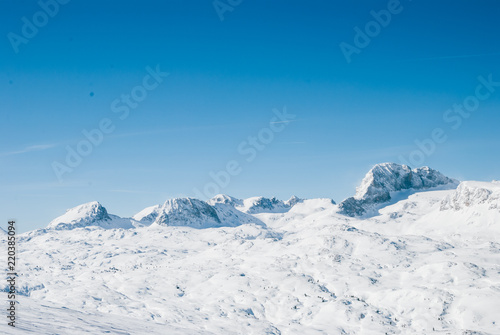 Snowy winter landscape in the Austrian Alps. Rocky plateau covered by sunlight. Bright white light reflected by snow © Yurii Zymovin