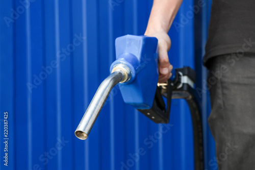Fuel pump in hand man on blue background. Petrol station. Holding fuel nozzle. 