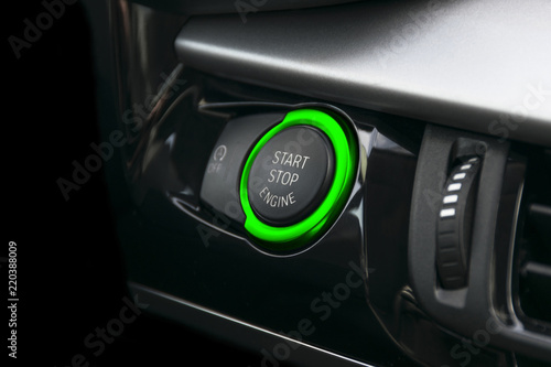 Car dashboard with focus on green engine start stop button. Car interior details. Car detailing © Aleksei