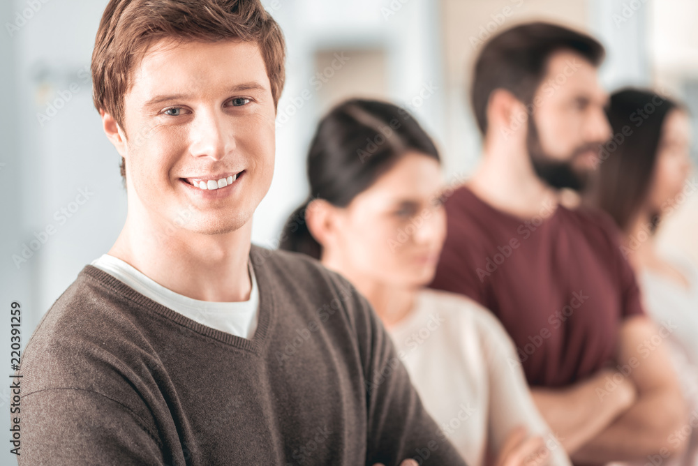 Team leader. Delighted handsome man smiling to you while leading his team Team leader. Delighted handsome man smiling to you while leading his team