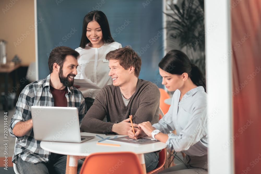 Productive cooperation. Joyful happy students talking to each other while preparing to exams together Productive cooperation. Joyful happy students talking to each other while preparing to exams together