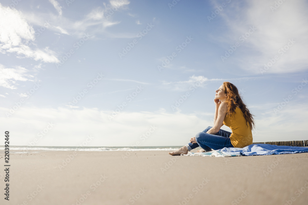 Woman sitting on the beach, enjoying the sun Woman sitting on the beach, enjoying the sun