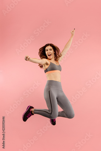 Fototapeta Naklejka Na Ścianę i Meble -  Freedom in moving. Mid-air shot of pretty happy young woman jumping and gesturing against orange studio background. Runnin girl in motion or movement. Human emotions and facial expressions concept