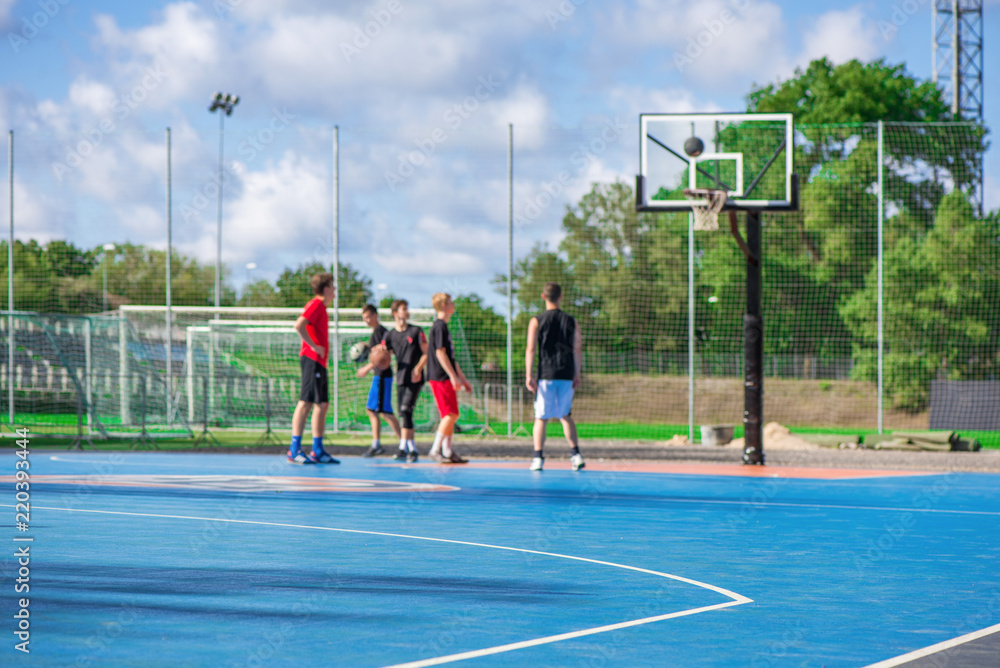 Fototapeta premium Abstract, blurry background of boys playing basketball in outdoor basketball court in park 